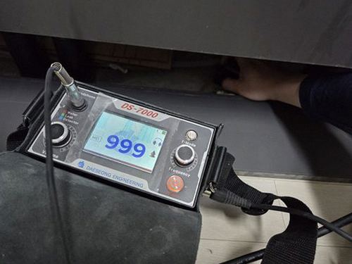 누수탐지 벽면의 수분 흔적과 누수 점검 장비를 살펴보는 모습