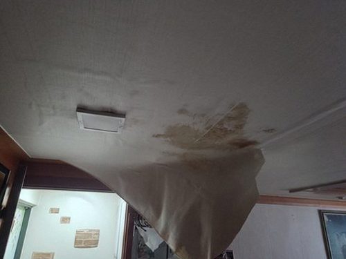 누수탐지 점검 기록을 정리한 노트와 벽면 사진을 비교하는 모습