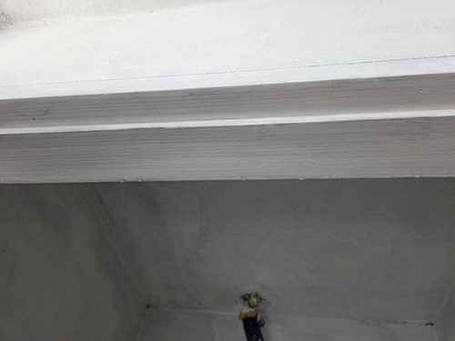 누수탐지 벽면과 바닥 경계에서 육안으로 물기 흔적을 점검하는 모습