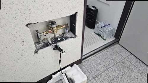 누수탐지 점검 결과를 정리한 기록지와 벽면 상태를 함께 확인하는 장면