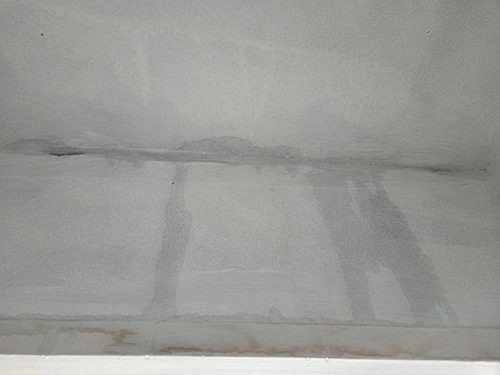 누수탐지 거실 천장 모서리에 번진 얼룩과 벽지 들뜸 상태를 기록하는 장면