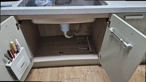 누수탐지 주방 하부장 내부의 배관 연결부와 바닥의 젖은 흔적을 살피는 현장 모습
