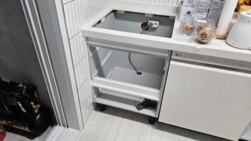 누수탐지 싱크대 하부장 바닥의 물기 흔적과 배관 연결부 점검 장면