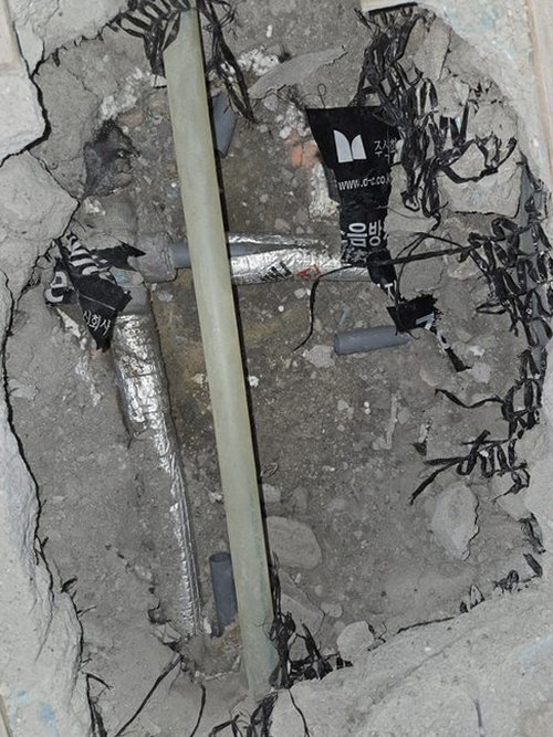 누수탐지 배관 점검을 위해 벽체를 살피는 작업 장면