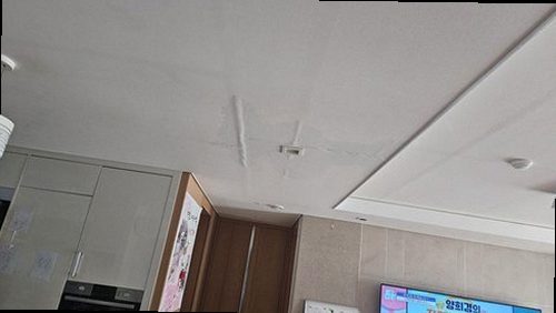 장안구 누수탐지 천장 모서리에 번진 물 얼룩과 벽지 들뜸을 살펴보는 모습