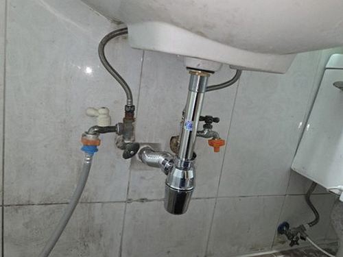 누수탐지 싱크대 하부장 배관 연결부의 물기 흔적을 육안으로 확인하는 모습
