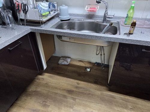 누수탐지 점검을 위해 싱크대 하부 수납물을 비우고 바닥 상태를 확인하는 모습