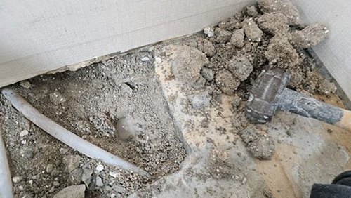 누수탐지 개방된 벽면에서 배관 연결부를 확인하는 장면